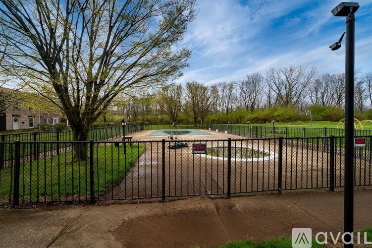 A black fence surrounds a playground with a basketball court.