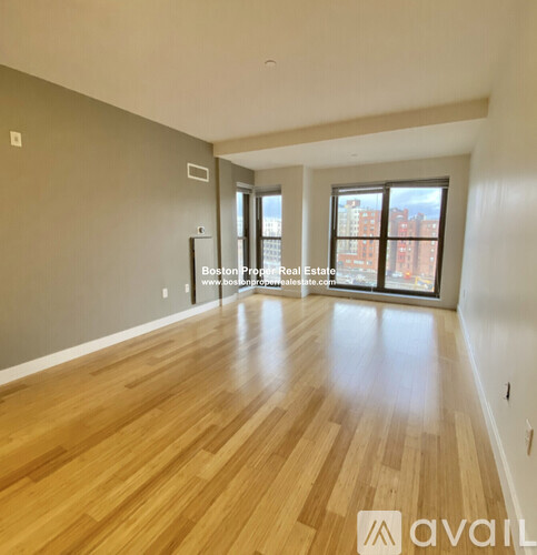 A spacious room with wooden flooring and a large window.