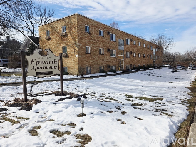 A sign for Epworth Apartments stands in front of a brick building with snow on the ground.