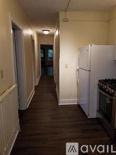 A long hallway with a refrigerator on the right side.