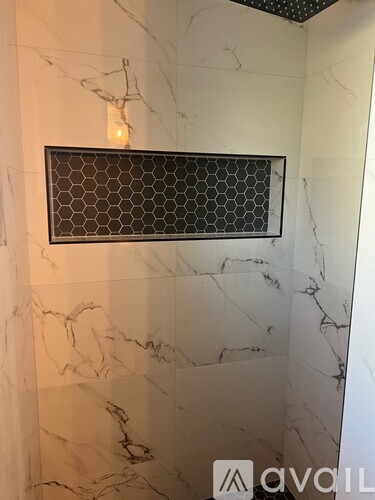 A bathroom with marble walls and a hexagonal tile shower enclosure.