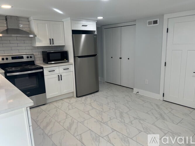 A kitchen with white cabinets and a marble floor.