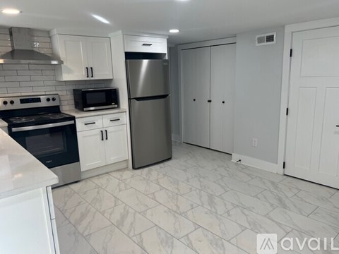 A kitchen with white cabinets and a marble floor.