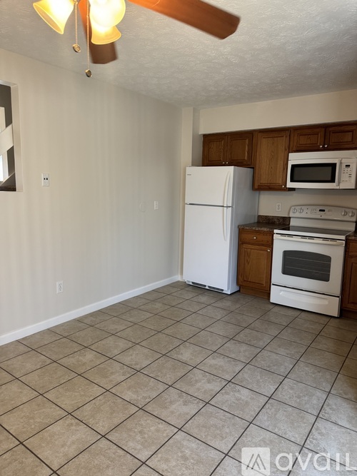 A kitchen with white appliances and brown cabinets.