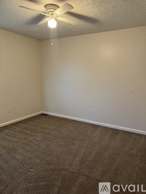 A room with a ceiling fan and carpeted floor.