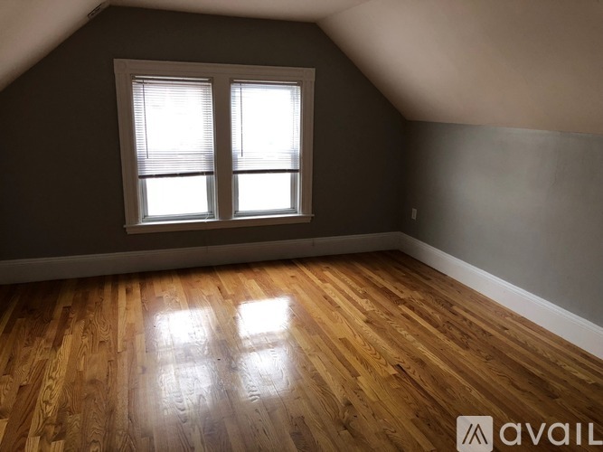 A room with wooden flooring and a window with blinds.