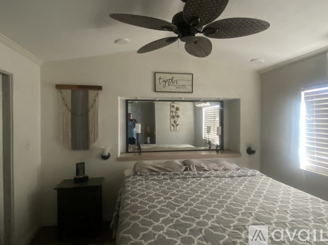 A bedroom with a large bed and a ceiling fan.