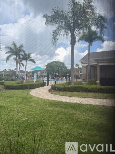 A grassy area with a building and palm trees in the background.