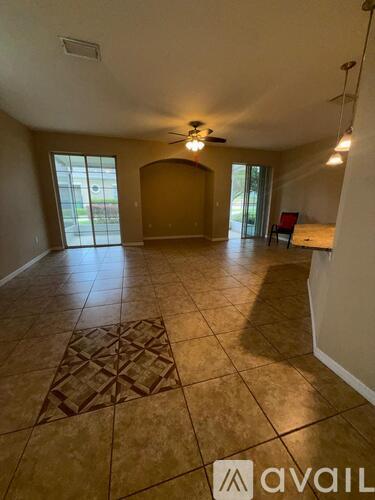 A spacious room with a tiled floor and a ceiling fan.