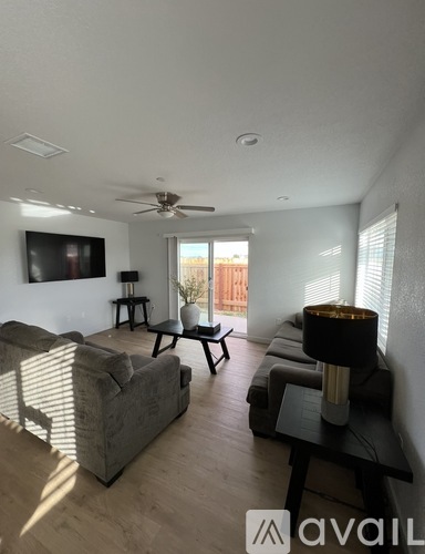 A living room with a grey couch, a black coffee table, and a flat screen TV mounted on the wall.