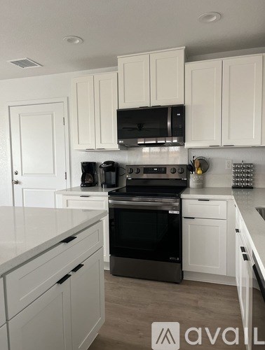 A kitchen with white cabinets and a black stove top oven.