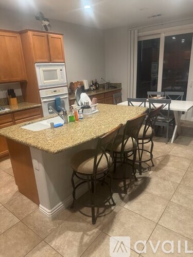 A kitchen with a granite countertop and bar stools.