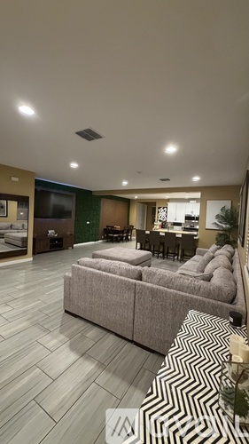 A living room with a grey sofa and a patterned rug.