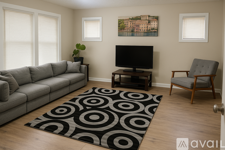 A living room with a grey sofa, a black and white rug, a wooden chair, and a painting on the wall.