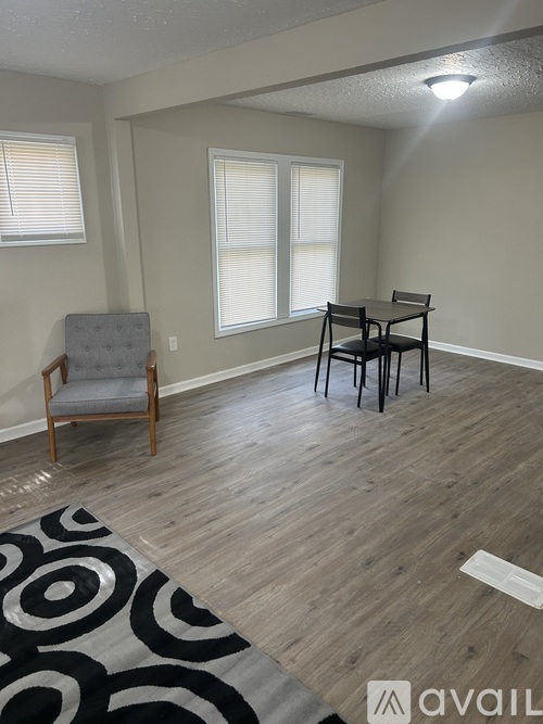 A room with a grey chair and a black and white rug.