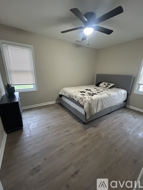A bedroom with a bed, a ceiling fan, and a window with blinds.