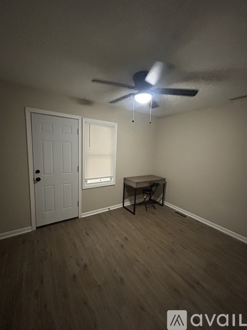 A room with a ceiling fan and a table with a chair.