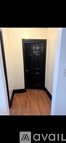 A black door in a room with wooden flooring.