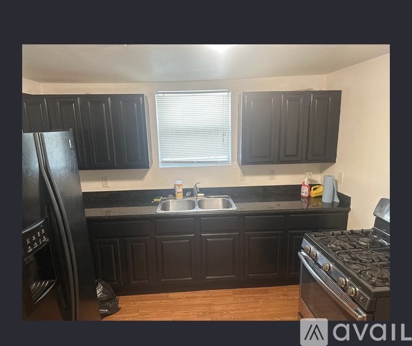 A kitchen with black cabinets and a black stove top oven.