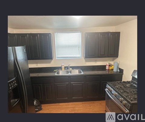 A kitchen with black cabinets and a black stove top oven.