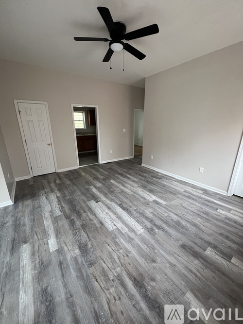 A room with a ceiling fan and wood flooring.