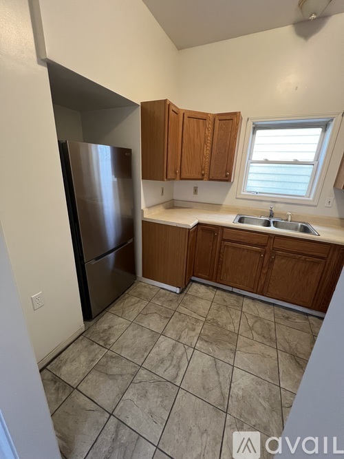 A kitchen with a stainless steel refrigerator and wooden cabinets.