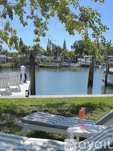 A glass of champagne sits on a table by a lake.