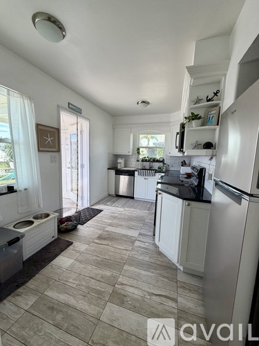 A kitchen with white cabinets and a tiled floor.