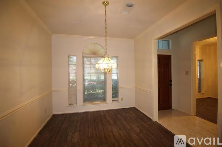 A room with a wooden floor and a chandelier hanging from the ceiling.