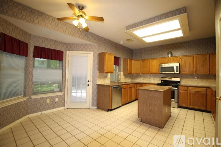 A kitchen with a white tile floor and wooden cabinets.