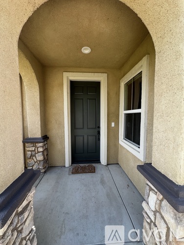 A black door is in the middle of a tan wall.