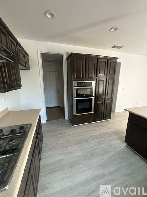 A kitchen with dark brown cabinets and a stove top oven.