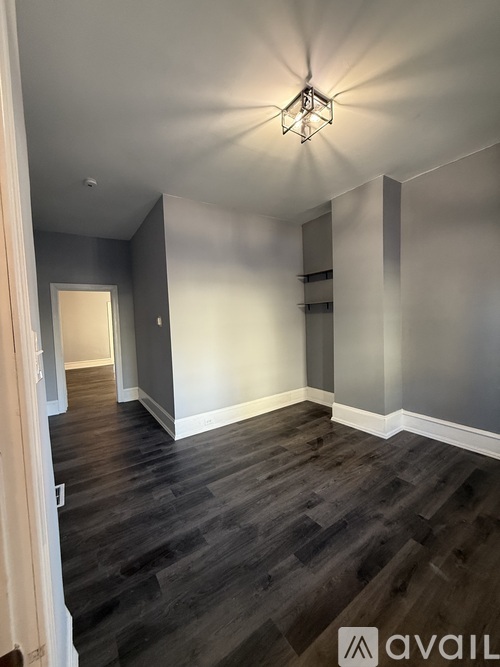 A hallway with wood flooring and a light fixture on the ceiling.