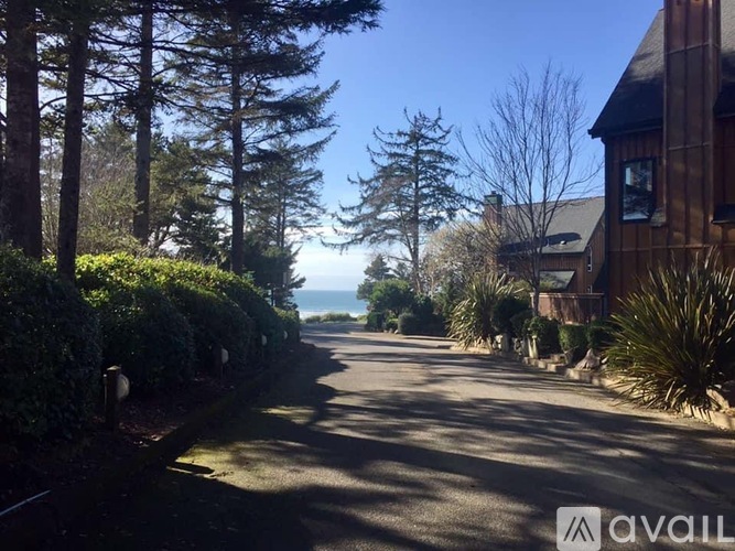 A tree-lined street with a house on the right.