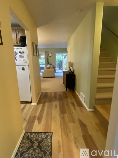 A hallway with a refrigerator and a staircase.