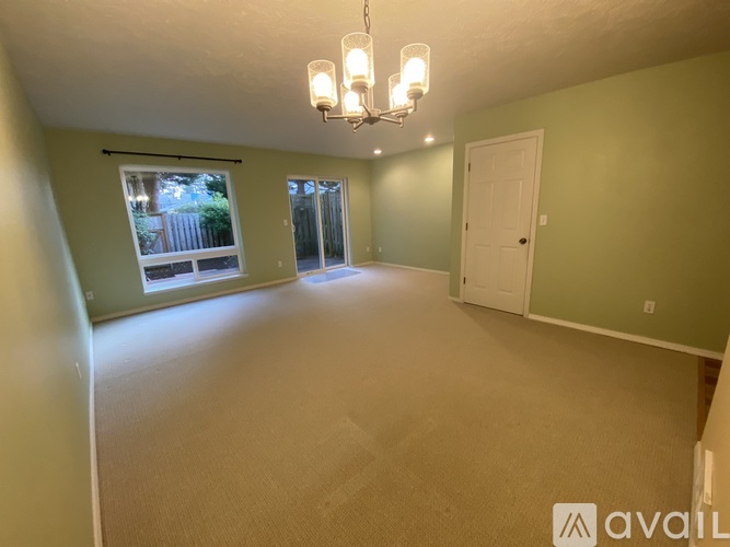 A room with a chandelier and a window overlooking a fence.
