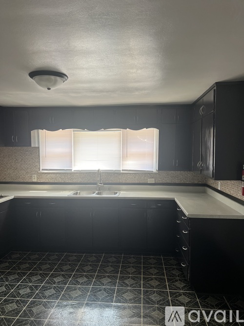 A kitchen with black cabinets and a white sink.