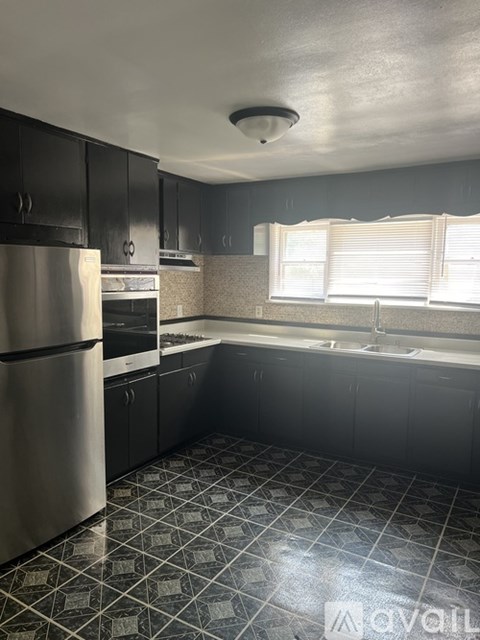 A kitchen with a stainless steel refrigerator and black cabinets.