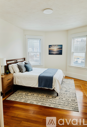 A bedroom with a bed, nightstand, and a picture on the wall.