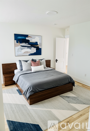 A bedroom with a large bed and a painting on the wall.
