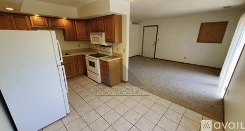 A carpeted room with a window and wooden trim.
