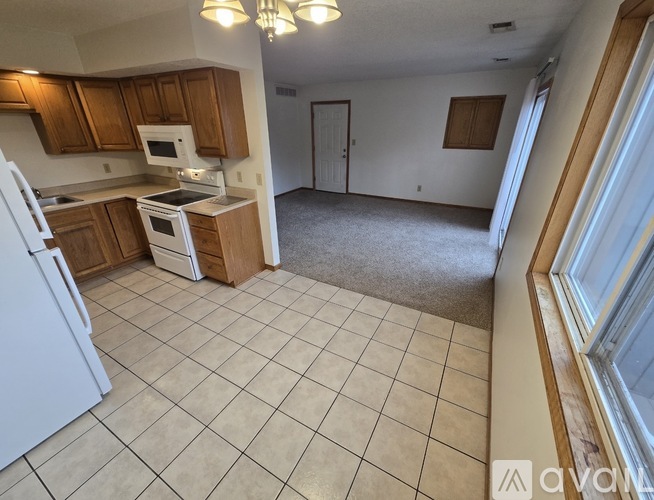 A kitchen with white appliances and wooden cabinets.