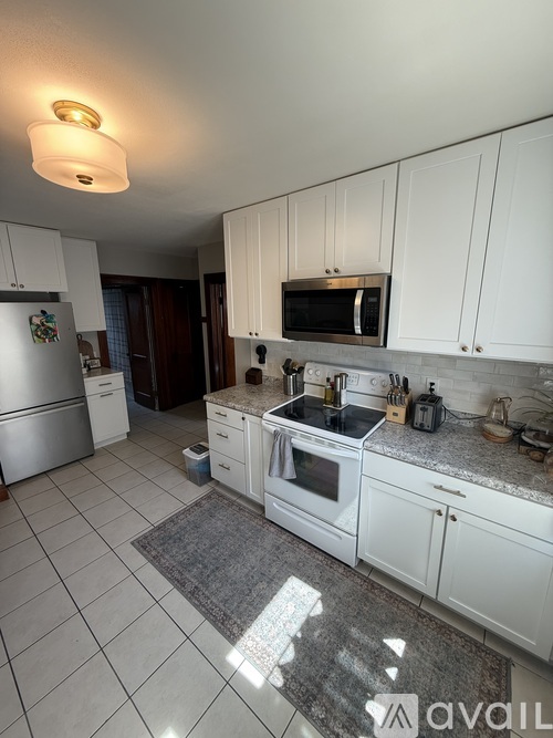 A kitchen with white cabinets and a refrigerator.