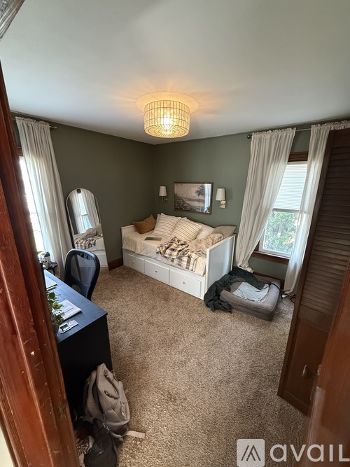 A bedroom with a bed, dresser, mirror, and window.