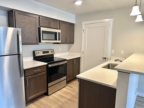 A kitchen with brown cabinets and a stainless steel refrigerator.
