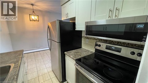 A kitchen with a black fridge, stove, and microwave.