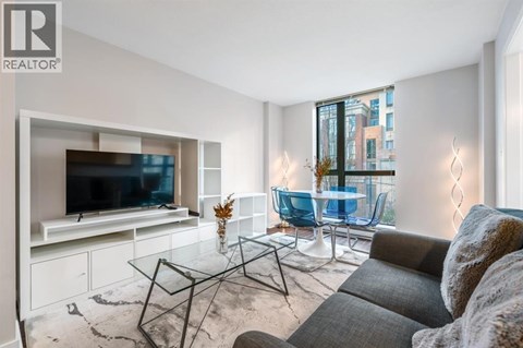 A living room with a grey couch and a glass coffee table.