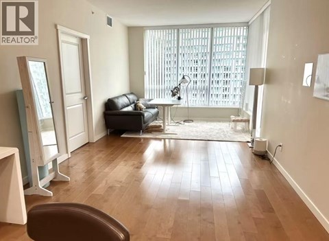 A living room with a brown leather couch and wooden floors.