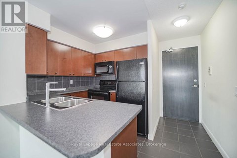 A kitchen with brown cabinets and a black refrigerator.
