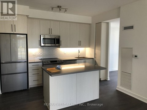 A modern kitchen with white cabinets and a stainless steel refrigerator.